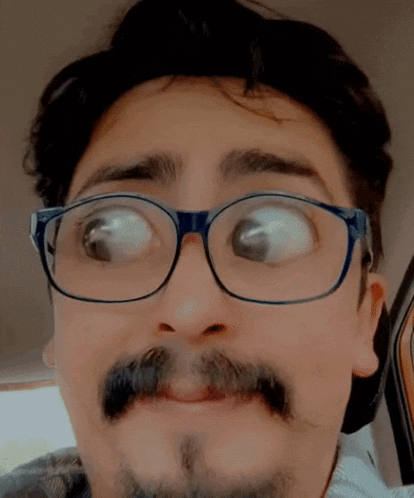 a man with glasses and a beard is making a face