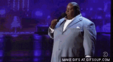 a man in a suit is singing into a microphone on a stage ..