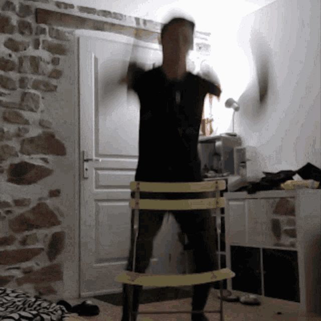 a man in a black shirt is standing on a chair