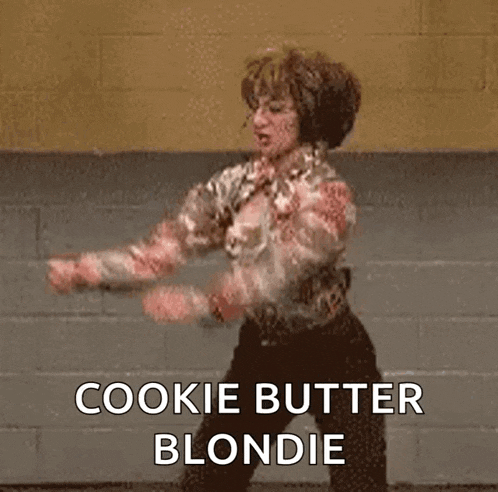 a woman is dancing in front of a brick wall and says cookie butter blondie .