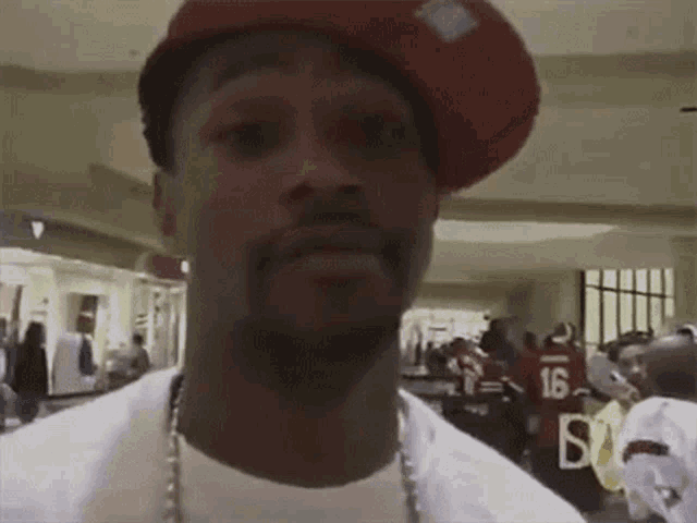 a man wearing a red hat and a white shirt is looking at the camera .