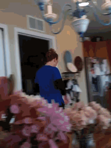 a woman in a blue shirt stands in a kitchen