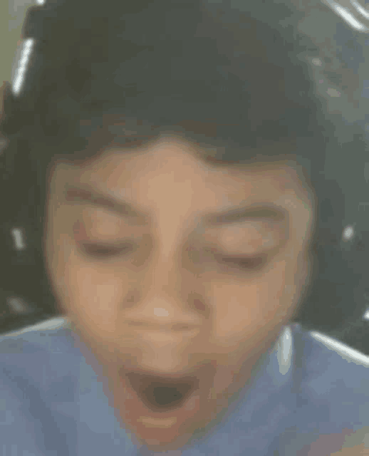 a close up of a young boy wearing headphones with his mouth open .