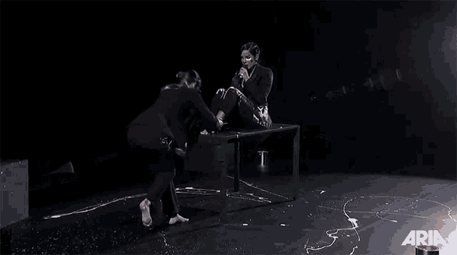 a woman is sitting on a table with aria written on the bottom