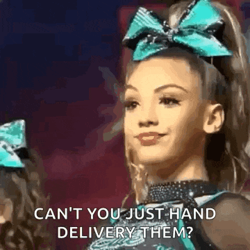 a cheerleader with a blue bow on her head is smiling and talking to another cheerleader .