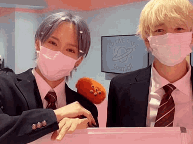 two people wearing masks in front of a sign that says cosmidl