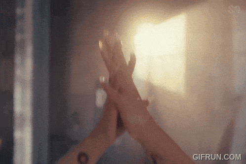 a woman is giving herself a high five in front of a mirror .