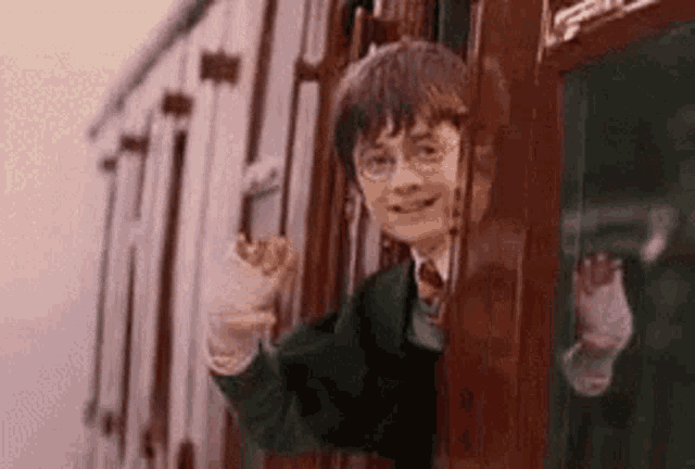 harry potter is looking out of a train window and waving .