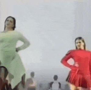 a blurry picture of two women dancing in front of a crowd of people .
