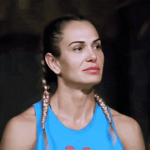 a woman with braids wearing a blue tank top looks to the side