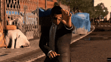 a man in a suit and tie is standing on a street with a blue tarp behind him