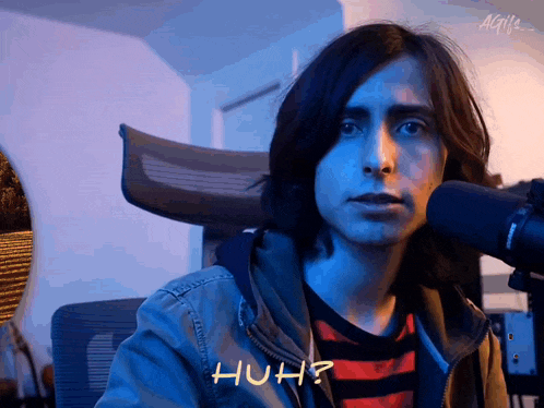 a man with long hair is sitting in front of a microphone and the word huh is on his face