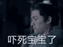 a man in a suit and tie is making a funny face in a dark room with chinese writing .