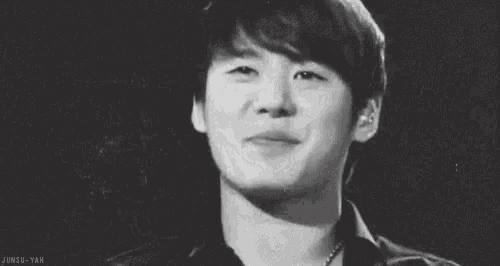 a black and white photo of a young man smiling with the caption junsu-yah