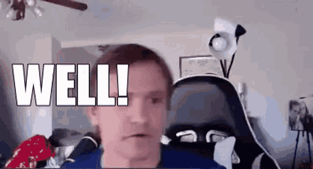 a man is sitting in a chair in front of a computer screen with the words `` well ! '' written on it .