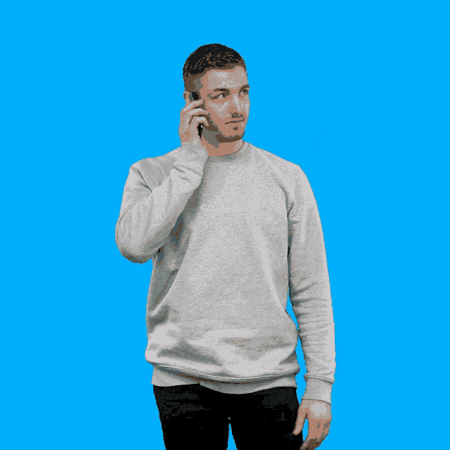 a man wearing a grey sweatshirt that says go splashy talks on a cell phone