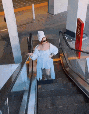 a woman with a towel on her head is riding an escalator