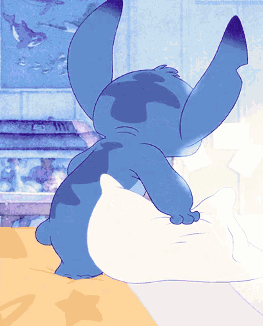 a cartoon of stitch sitting on a bed with a pillow
