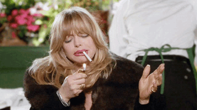 a woman in a fur coat is lighting a cigarette with her eyes closed