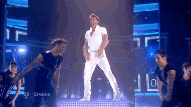 a man in a white shirt is dancing on a stage in front of a screen that says eurovision tv