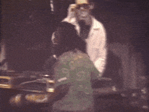 a man in a white coat stands next to a woman in a green shirt with the number 80 on it