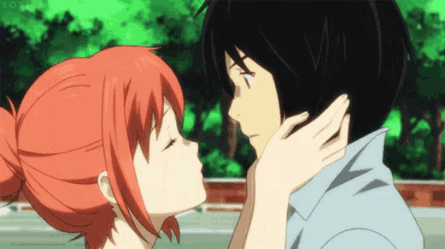 a girl with red hair is kissing a boy on the cheek