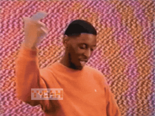 a man wearing an orange sweater says yeah