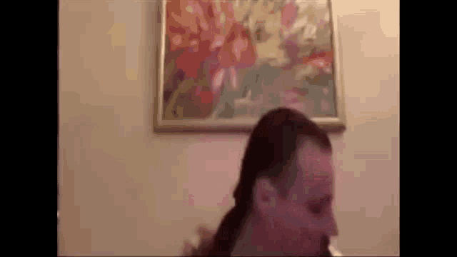 a woman is standing in front of a framed picture of flowers