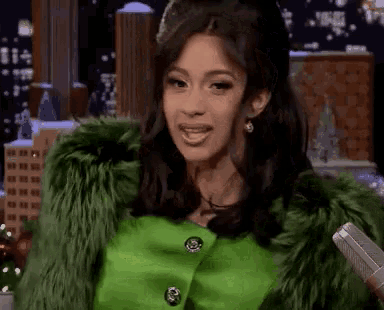 a woman wearing a green fur coat is holding a microphone .
