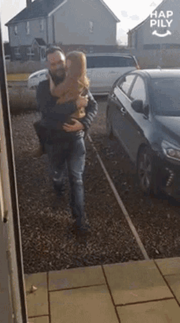 a man is holding a little girl in his arms in front of a car with hap pily written on it