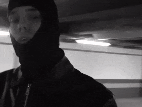 a man wearing a ski mask is standing in a parking garage .