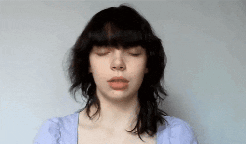 a woman with her eyes closed is wearing a blue top