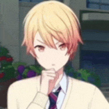 a boy with blonde hair and red eyes is wearing a sweater and tie and holding his hand to his chin .