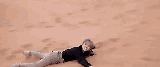 a person is laying in the sand in the desert .
