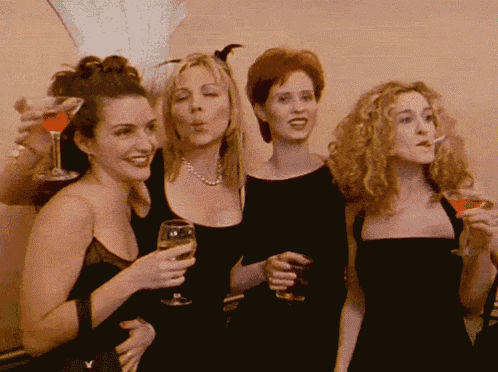 a group of women are standing next to each other drinking wine