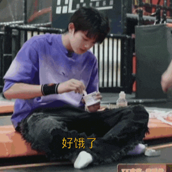 a young man in a purple shirt sits on a trampoline eating food
