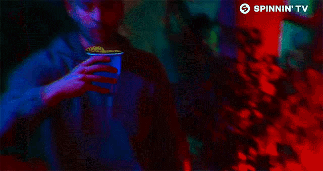 a man drinking from a cup with spinnin ' tv on the bottom right