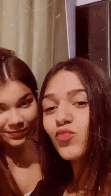 two young women are posing for a picture together and one has a nose ring .