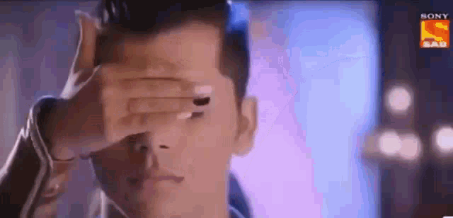 a man is covering his eyes with his hand while a woman looks on .