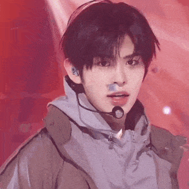 a close up of a young man wearing a microphone and a jacket on a stage .