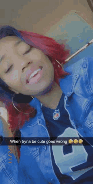 a woman with red hair is taking a selfie while wearing a blue jacket and a football jersey .