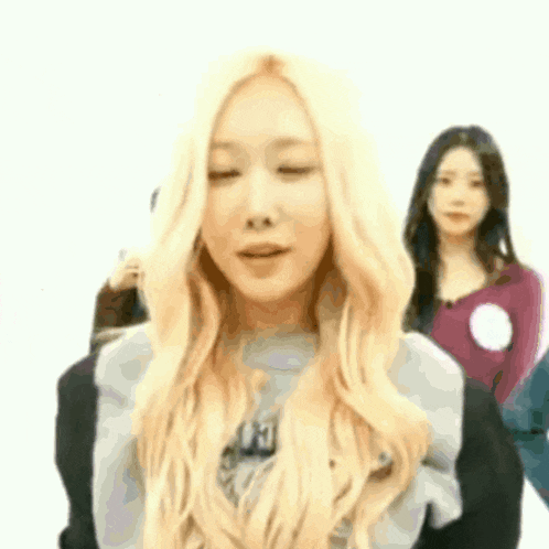 a woman with long blonde hair is standing in front of a group of people .