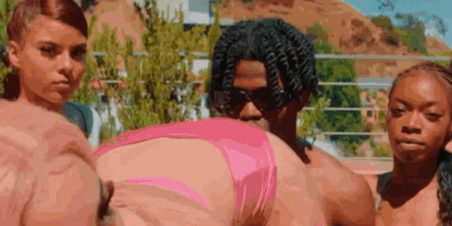 a man in a pink bikini is surrounded by women .