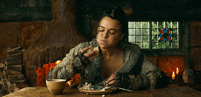 a woman is sitting at a table eating a piece of food