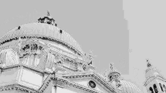 a black and white photo of a church with a dome and a bell tower .