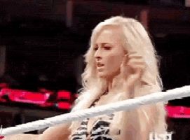 a woman is sitting in a boxing ring with a white rope around her neck .