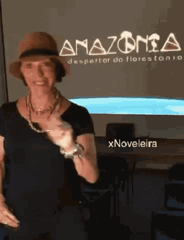 a woman wearing a hat is standing in front of a screen that says amazonia