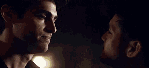 two men are looking into each other 's eyes in the dark .