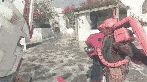 a red robot is standing in front of a white building with flowers