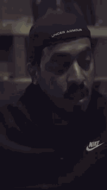 a man wearing a black under armour hat and a nike shirt